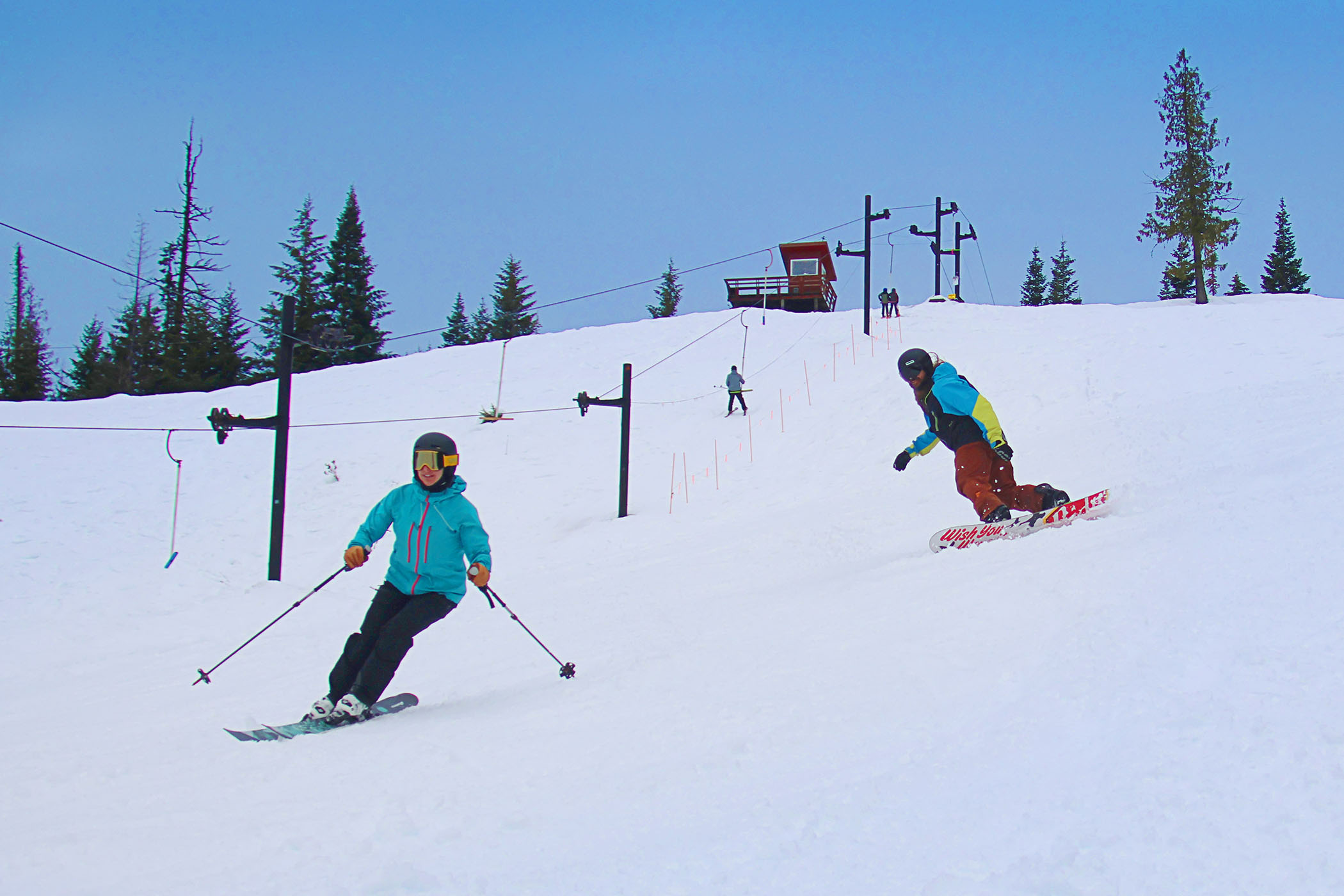 Skier and snowboarder descend a run at Bald Mountain Ski Area
